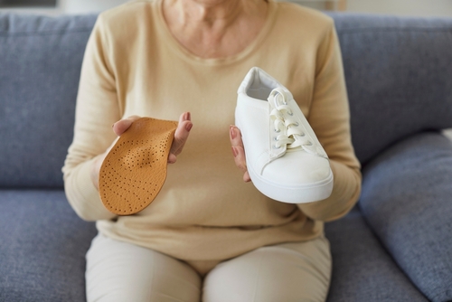 Elderly patient holding personalized orthotics designed for foot support