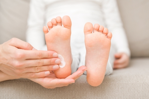 Parent applying moisturizer to a child's foot to maintain healthy skin